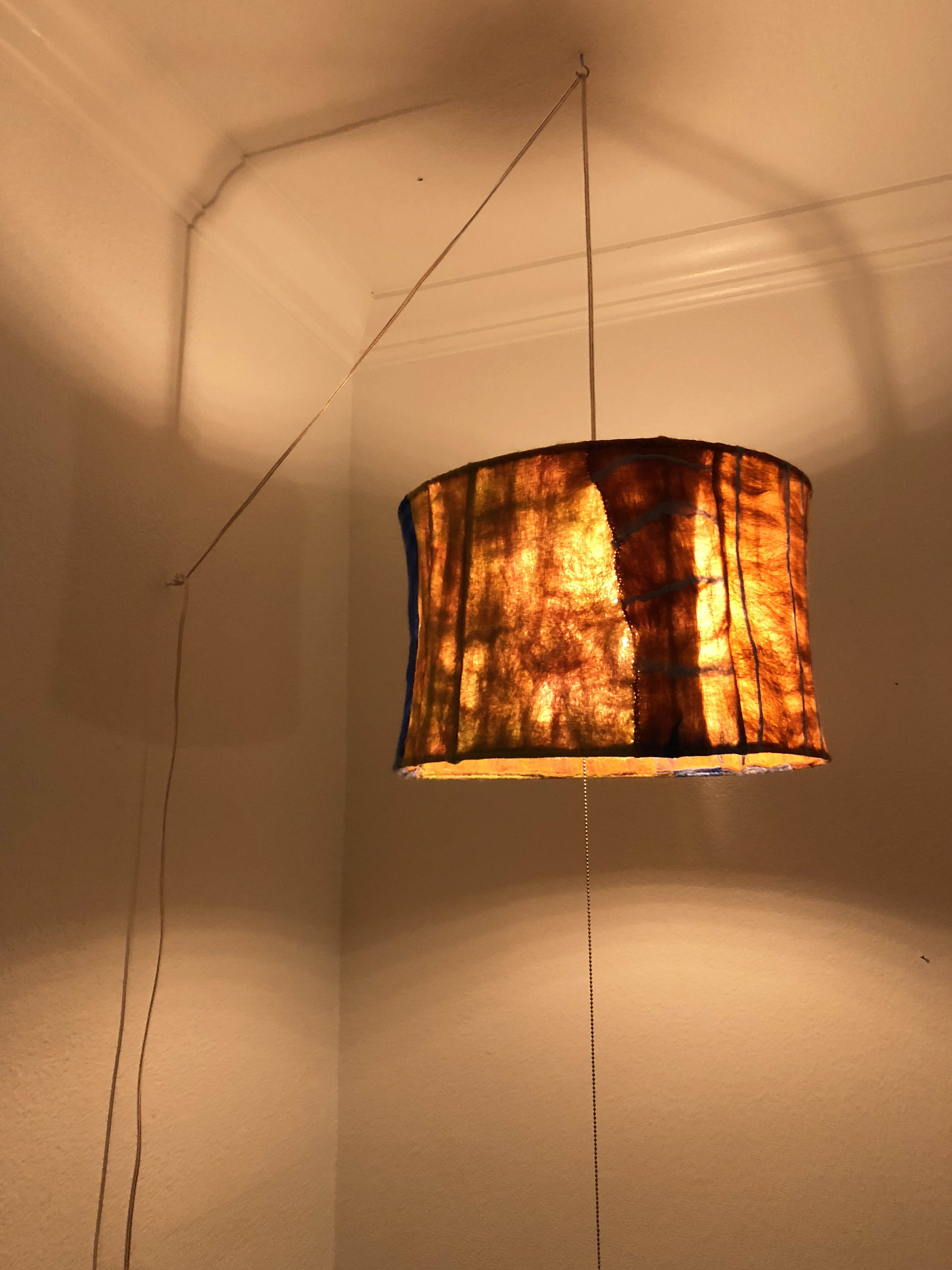 Detail of a felt lamp hanging from the ceiling of a kitchen emitting warm light